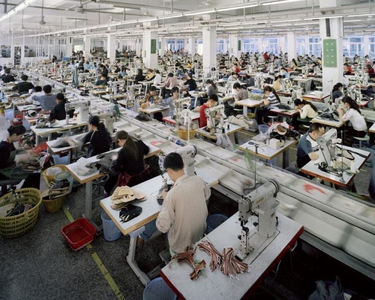 Lots of people working in a apparel factory and stitching clothes.