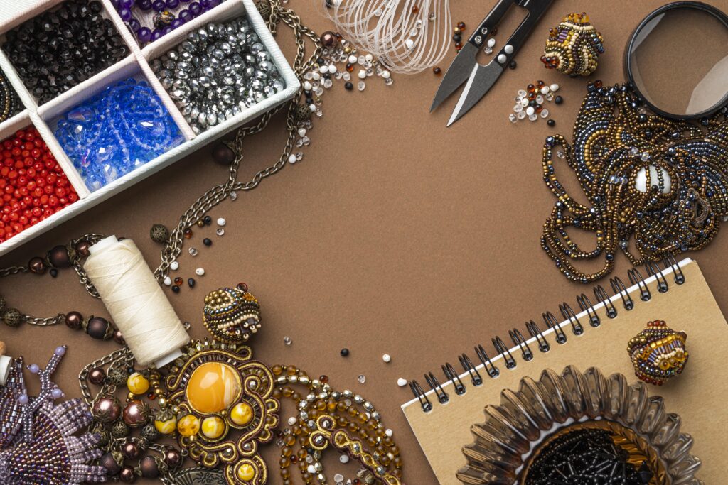 Flat lay of beadwork essentials, including colorful beads, scissors, threads, and handmade jewelry on a brown background, ideal for crafting and designing enthusiasts.