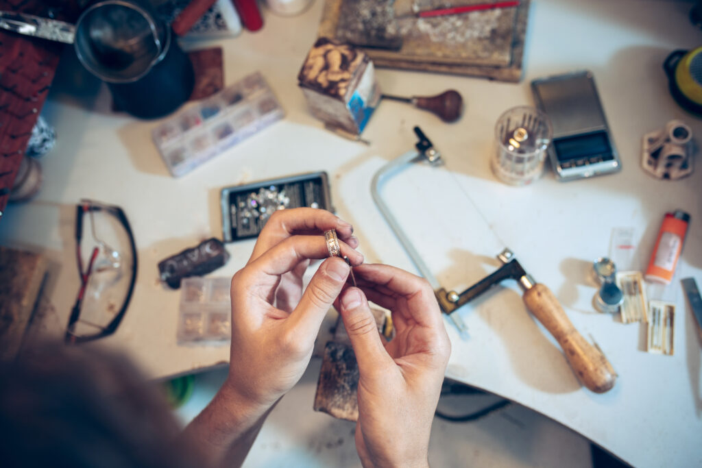 Different goldsmiths tools on the jewelry workplace. Jeweler at work in jewelry. Desktop for craft jewelry making with professional tools. Close up view of tools.